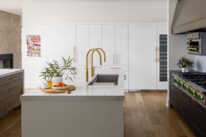 Custom kitchen with wine cooler, black and white cabinetry, white countertops and gold hardware