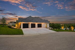 View of 3 car garage and driveway at night of Belton MO custom built home